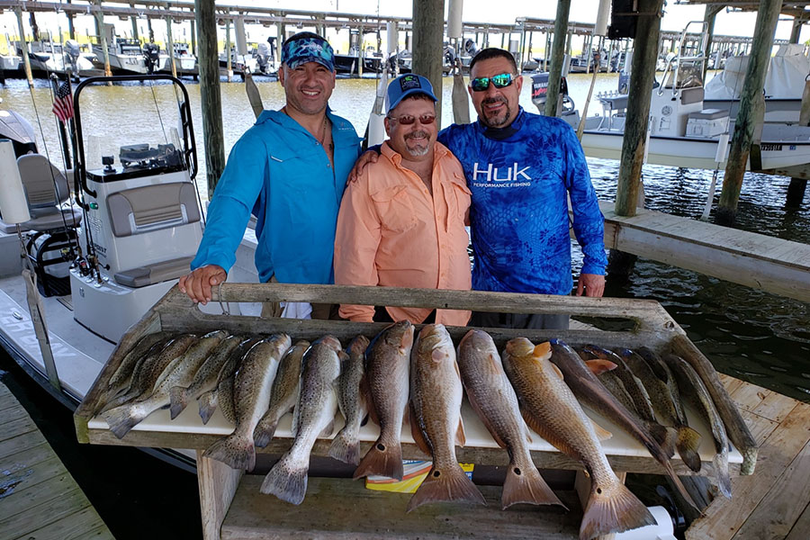 three fishermen stading behind a table with their catch of the day