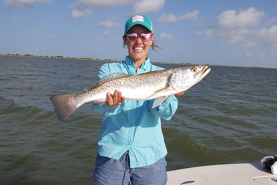 happy woman holding up a fish she just caught