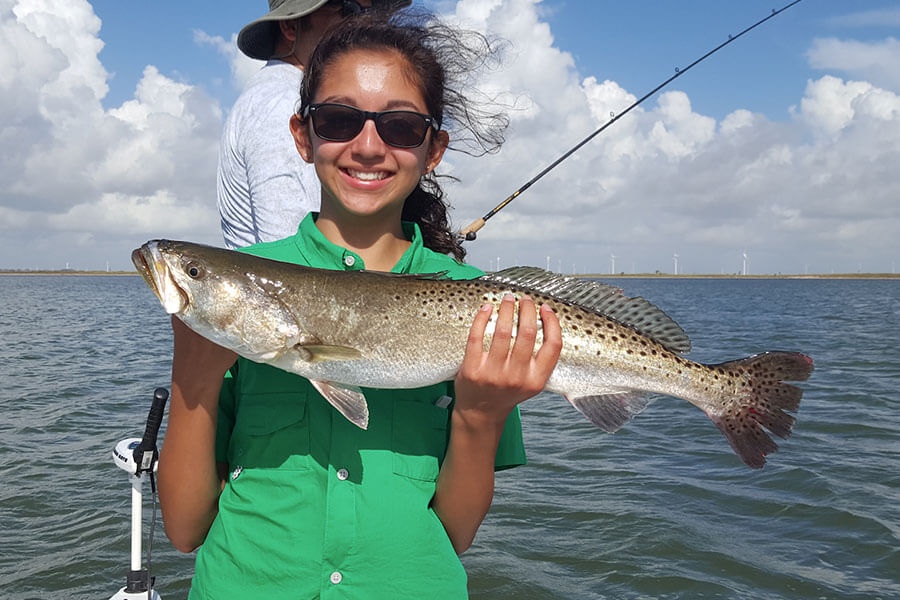 girl holding a speckled trout in corpus christi texas